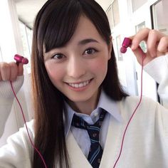 a woman with long hair wearing headphones and smiling at the camera while standing in front of a mirror