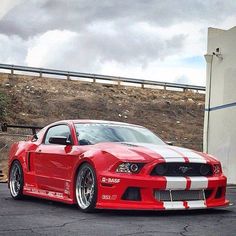 a red and white mustang parked in front of a building