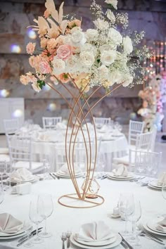 an elegant centerpiece with white and pink flowers on a round table in a banquet hall