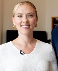 a woman in a white sweater smiles at the camera