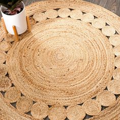 a round rug on the floor with a plant in it next to a white cup