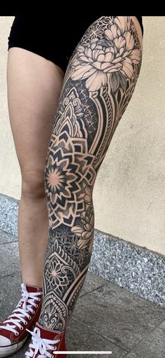 a woman's legs with tattoos on them and flowers in the middle of her leg