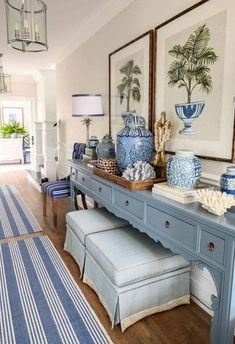 a blue and white entryway with artwork on the wall, bench and stools