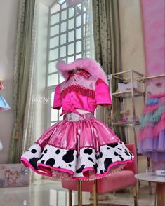 a pink dress with black and white polka dots on the skirt is sitting on a chair