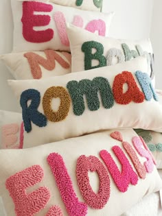 pillows with the word love spelled out in different colors and sizes, all stacked on top of each other