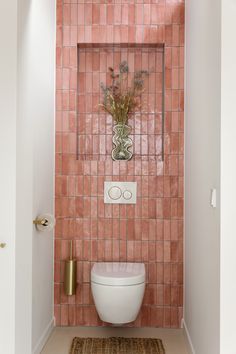 a white toilet sitting in a bathroom next to a pink tiled wall and gold accents