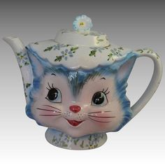 a ceramic teapot with a cat's face painted on the front and sides