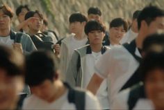 a group of young men walking down a street in front of a crowd of people