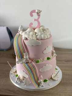 a pink cake with clouds and rainbows on top