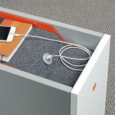 an orange and white box with a cell phone in it's compartment on the floor