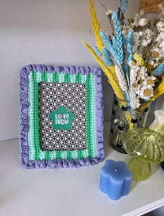 there is a blue and green square on the table next to some vases with flowers