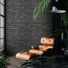 an office chair and ottoman in front of a brick wall with potted palm tree