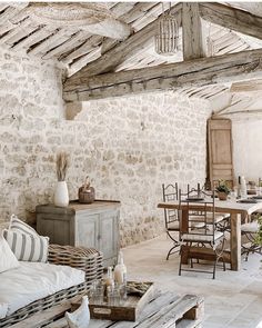 a living room filled with lots of furniture next to a stone wall and wooden beams