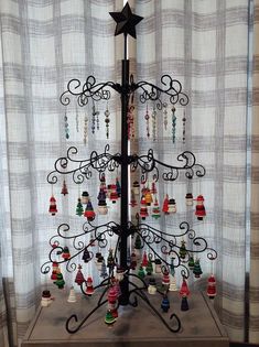 a christmas tree with bells hanging from it's sides in front of a window