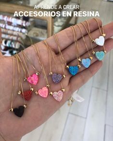 a person is holding several heart shaped necklaces in their hand with the words, apprene a crear accesioros en resina