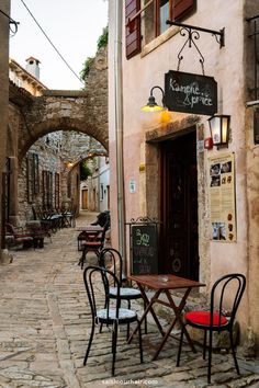 an alleyway with tables and chairs on the cobblestone street in front of a restaurant