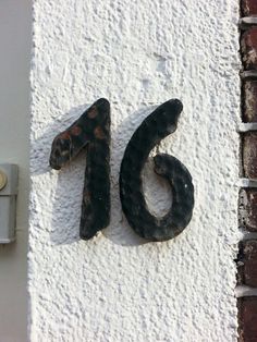 the number twenty five is painted black on a white wall and has rusted metal letters