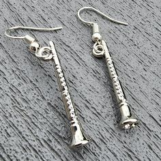 Clarinet charms hang from silver colored ear wire. The clarinets are three dimensional. The earrings are 1.75 inches long. Clarinet Jewelry, Clarinets, Orange Scent, Etsy Earrings Dangle, May 27, Ear Wire, Earrings Silver, Shades Of Green, Purple Color