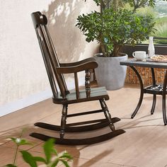 a rocking chair sitting on top of a hard wood floor next to a table and potted plant