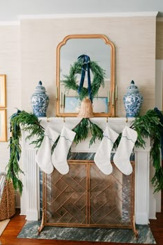 stockings hung on the mantle in front of a mirror and fireplace mantel decorated with greenery