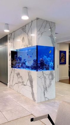 a fish tank in the middle of a room with marble walls and flooring, along with an aquarium