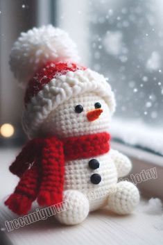 a crocheted snowman sitting on top of a window sill