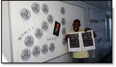 a man holding up two pictures in front of a whiteboard with words on it