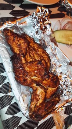 some meat is sitting on tin foil next to a banana and other food items in the background