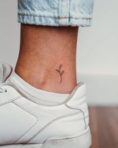 a woman's ankle with a small flower tattoo on her left side ribcage