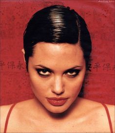 a close up of a person wearing a red top and looking at the camera with an evil look on her face