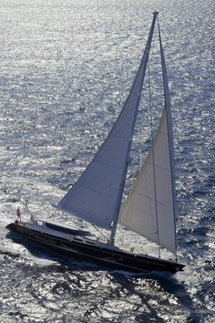 a sailboat sailing in the ocean with white sails on it's back end