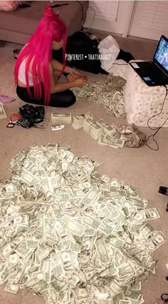 a woman with pink hair sitting on the floor surrounded by money