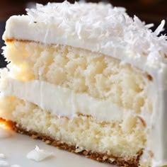 a piece of cake with white frosting and coconut on the top is sitting on a plate