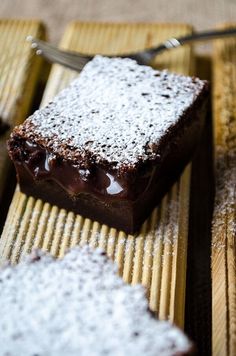 there is a piece of chocolate cake with powdered sugar on top and spoon next to it