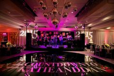 the dance floor is lit up with purple lights and chandeliers for an event