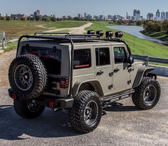 a jeep parked on the side of a road in front of a cityscape