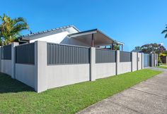 a fenced in area with grass and palm trees on the other side of it