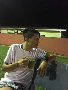 a man sitting on a bench holding a drink