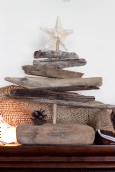 a christmas tree made out of driftwood on top of a mantle with a lit candle