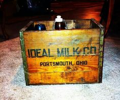 a wooden crate sitting on top of a carpeted floor next to a bottle of beer