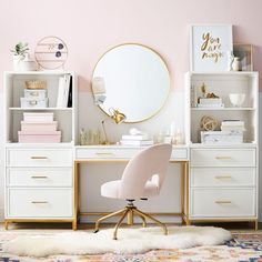 a white desk with gold accents and a round mirror on the wall above it in a pink room