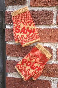 two knitted mittens hanging on a brick wall