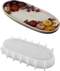 a white tray with flowers on it next to a candle holder filled with dried flowers