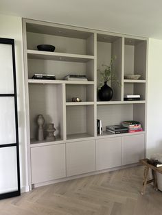 a living room filled with lots of white bookshelves next to a wooden table