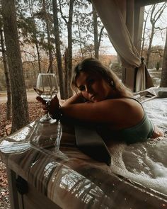 a woman laying in a hot tub with a glass of wine next to her face