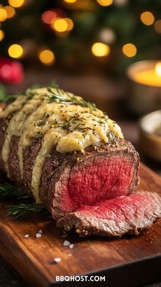 a large piece of steak on a wooden cutting board with christmas lights in the background