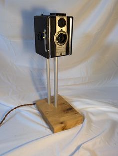 an old fashioned camera sitting on top of a wooden stand with two metal poles attached to it