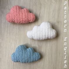 three crocheted clouds sitting on top of a wooden table