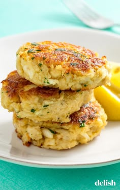 two crab cakes stacked on top of each other with lemon wedges next to them