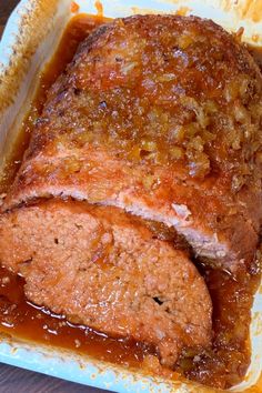 meatloaf covered in gravy sitting on top of a white plate